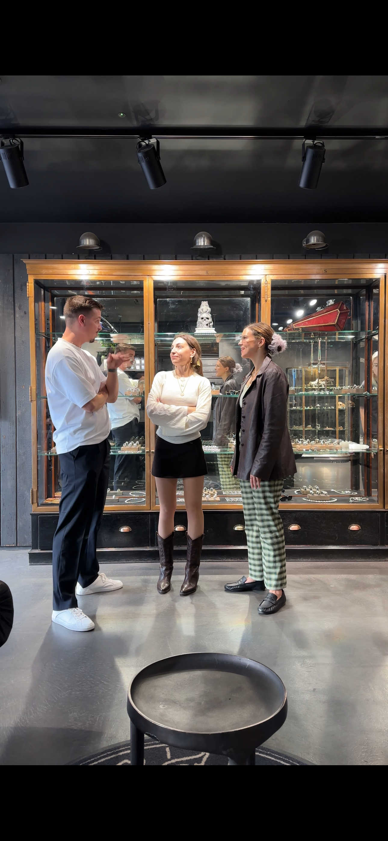 Three members chatting in front of a vintage glass display cabinet during a coworking day at Fora London.